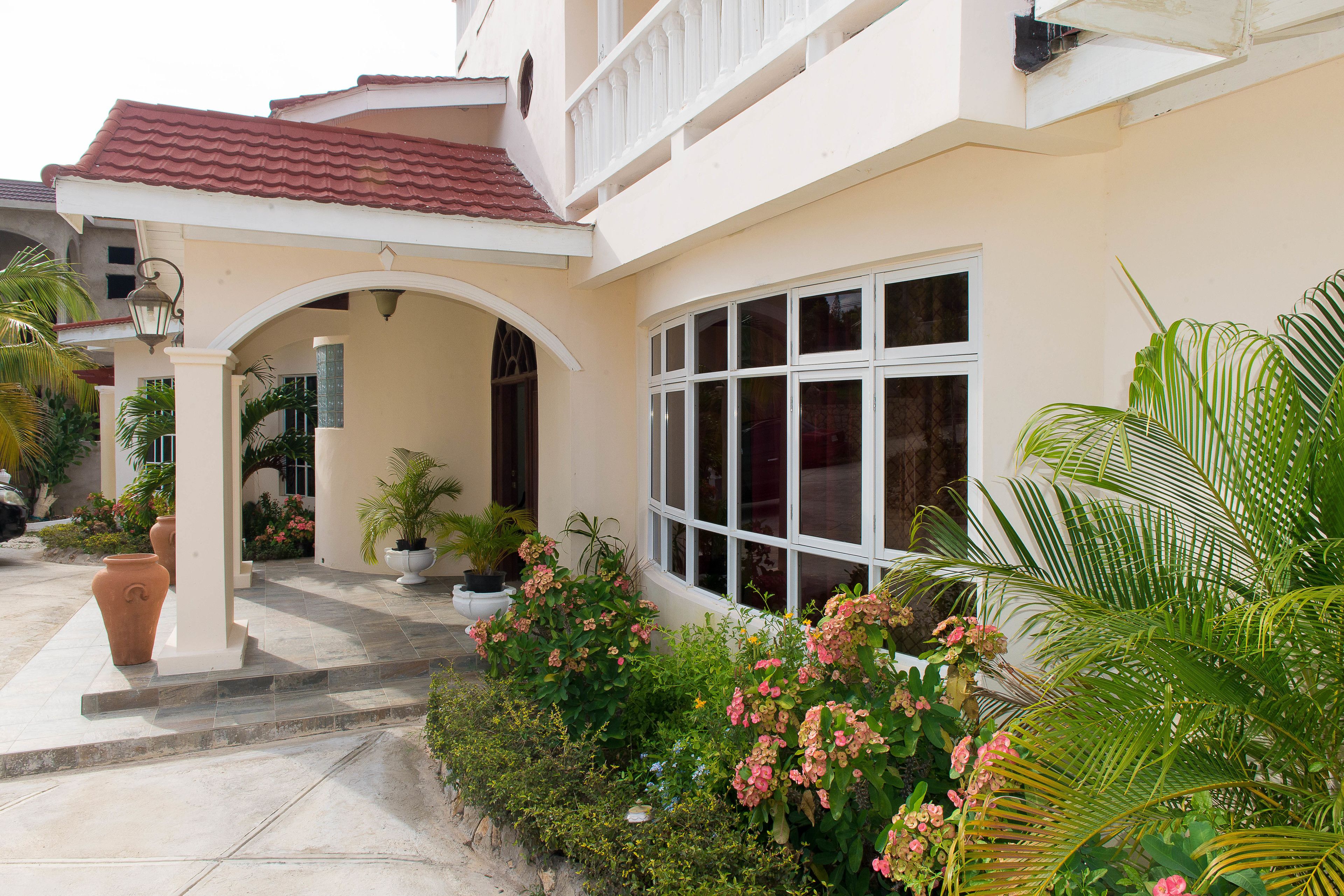 A house with a red-tiled roof, a covered porch with a white railing, and large windows.