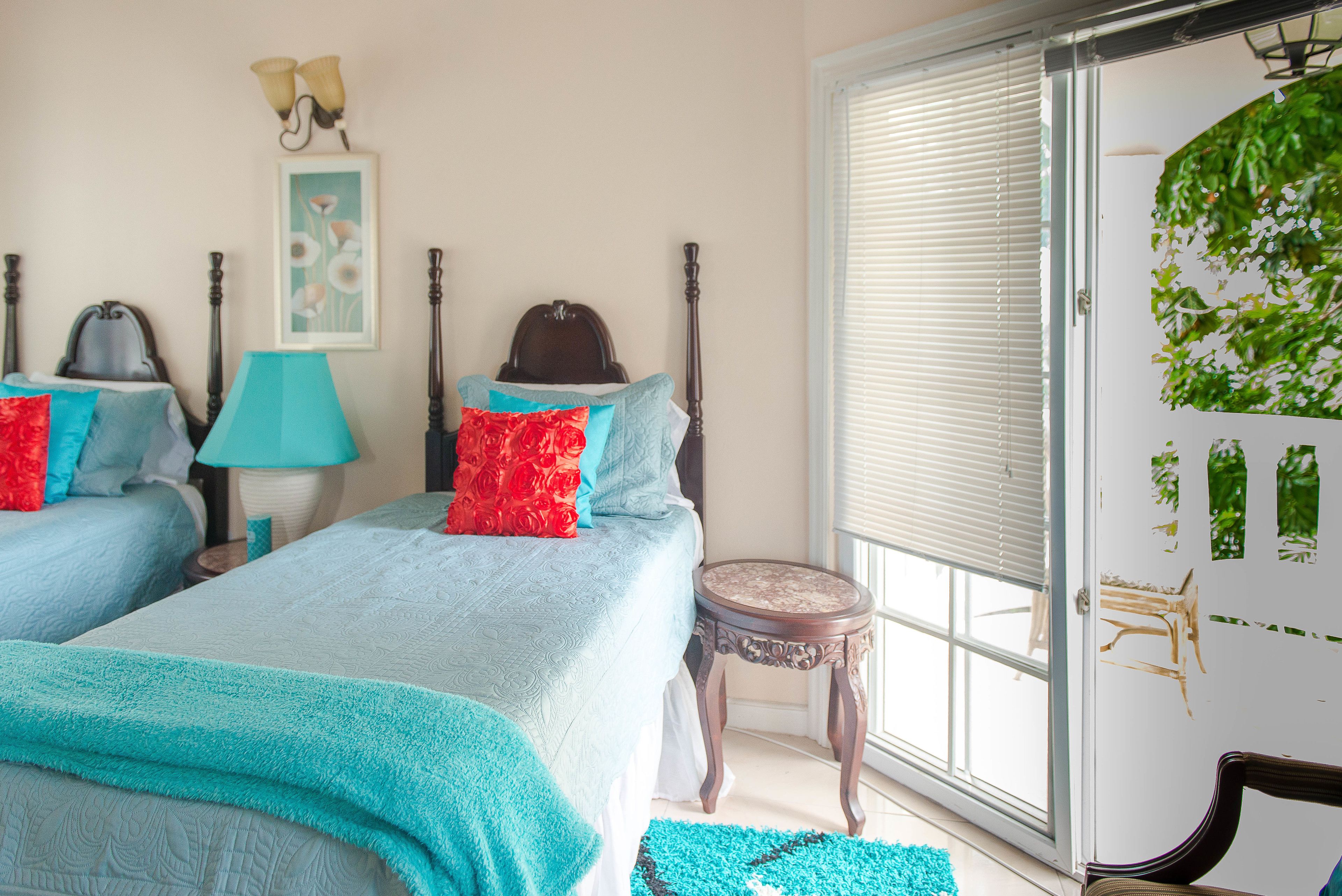 A bedroom with two beds, a small round table, and a window with blinds.