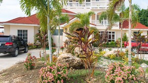 A two-story building with a red-tiled roof, a balcony, and a landscaped garden with tropical plants and flowers. - Khastle Khodero (Montego Bay)