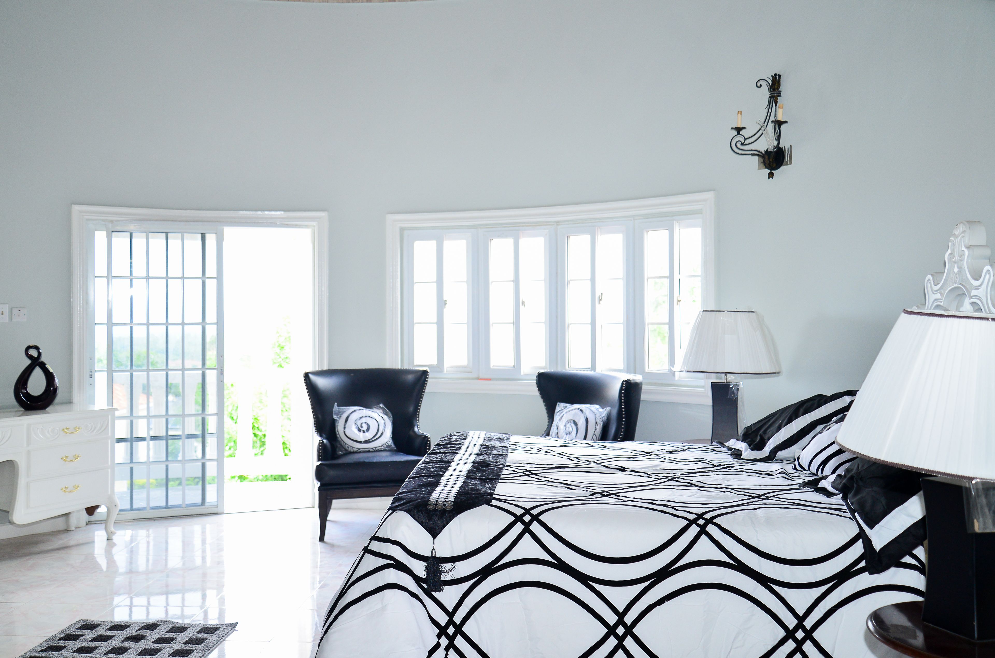 Une chambre à coucher avec un grand lit, deux chaises, une table de chevet et une fenêtre donnant sur un beau paysage.
