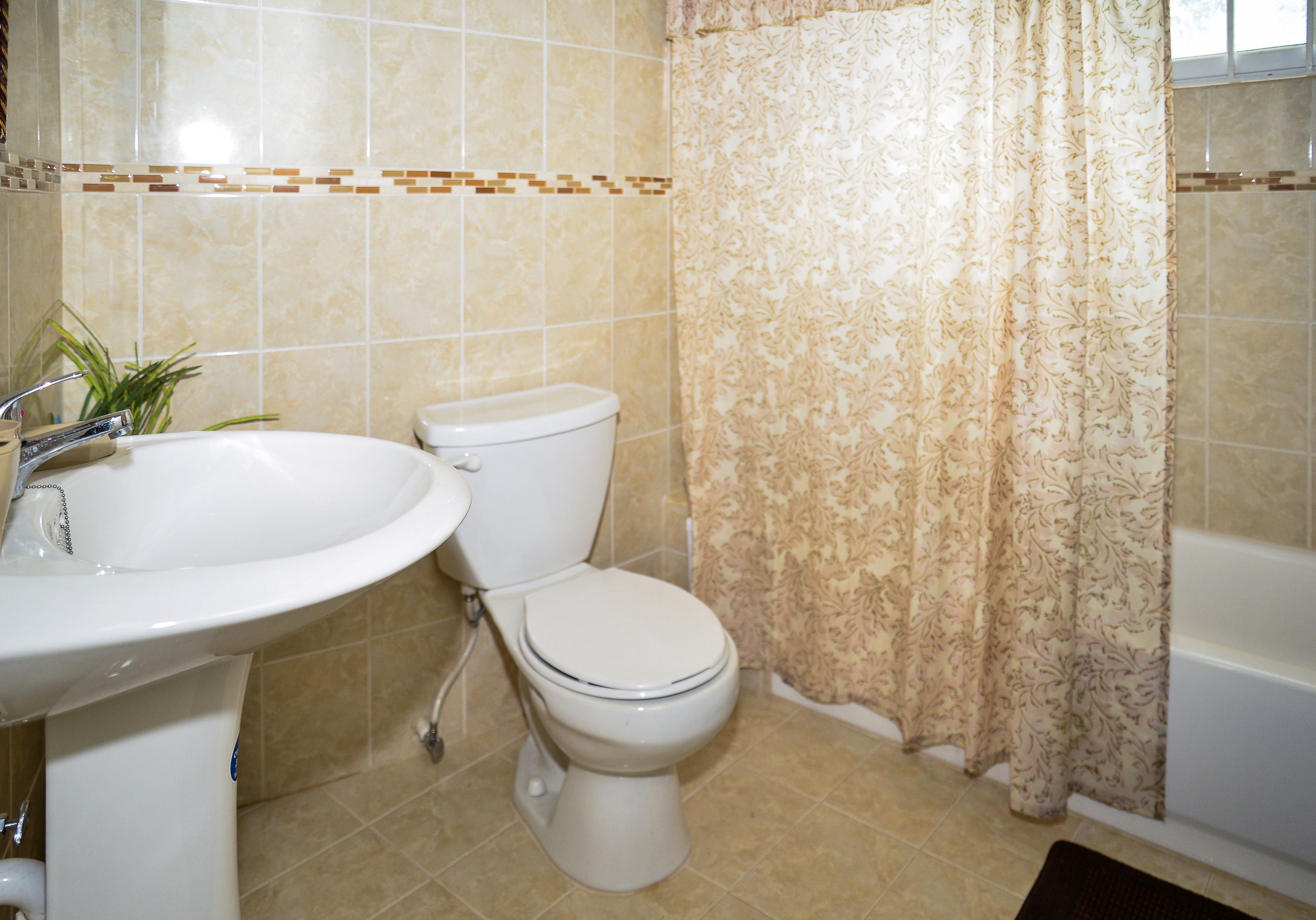 Et badeværelse med vask, toilet og badekar.