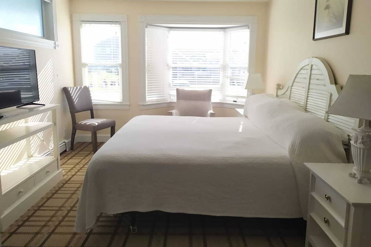 Een hotelkamer met een groot bed, een televisie, een stoel en een bureau.
