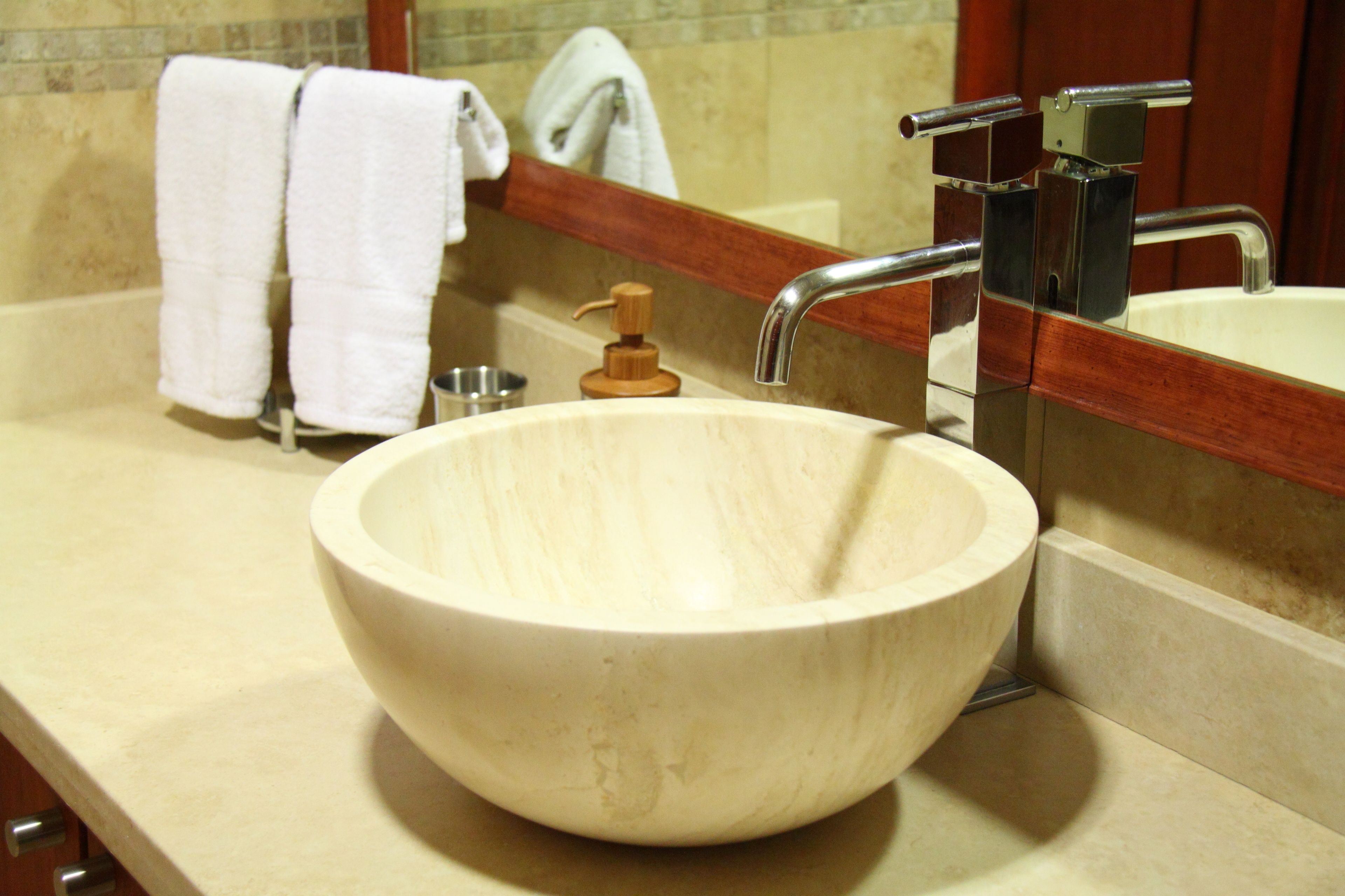 A bathroom with a large wooden bowl sink, a mirror, and two white towels hanging on a towel rack.