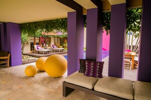 Ein stilvoller Lounge-Bereich mit Pool, violetten Wänden und bequemen Sitzmöglichkeiten.