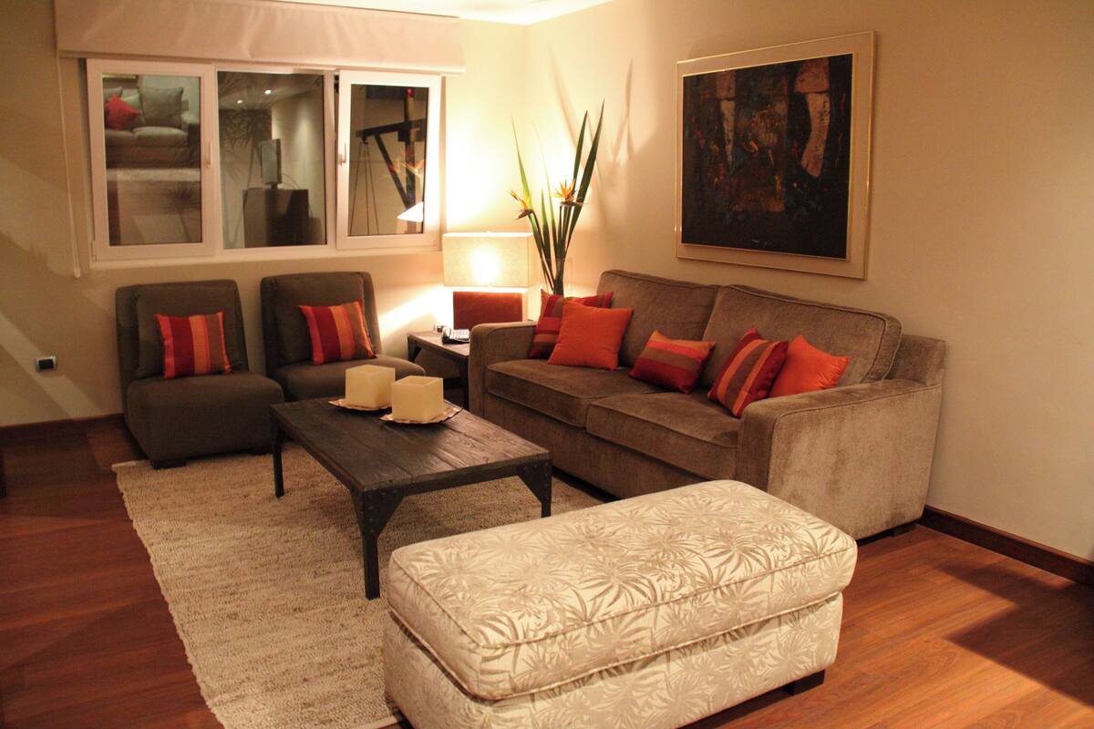 Una sala de estar con un sofá, dos sillones, una mesita de centro y un jarrón decorativo.