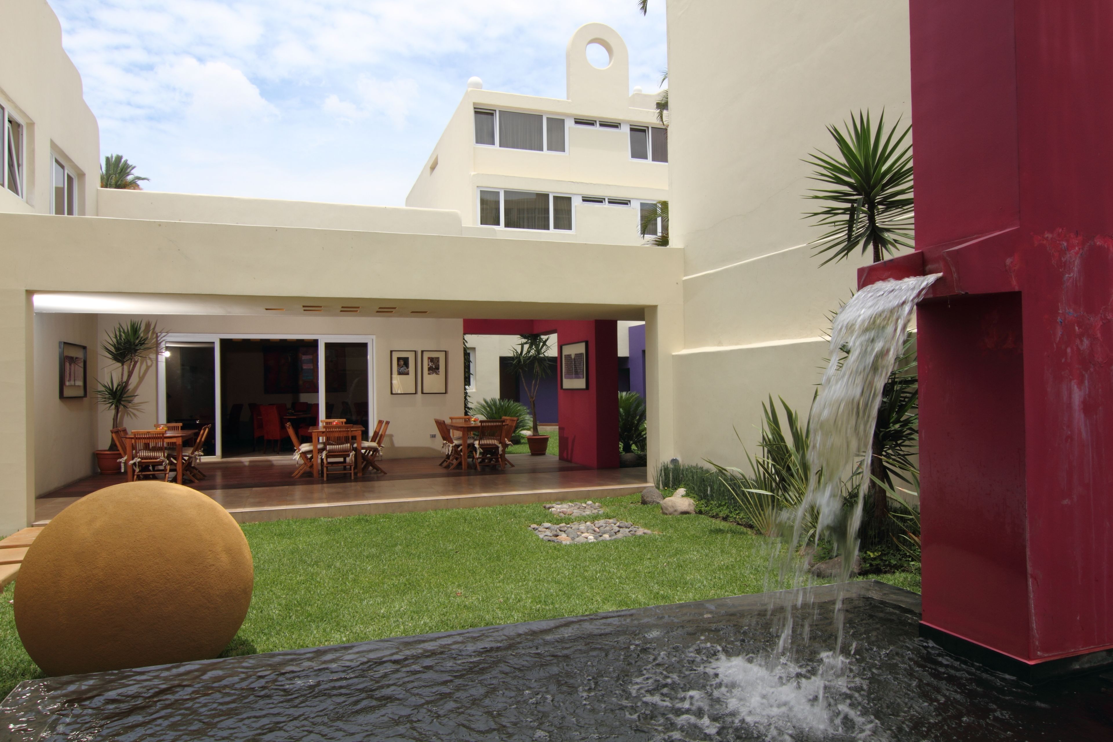 A courtyard with a water feature, outdoor seating, and a building with a unique architectural design.