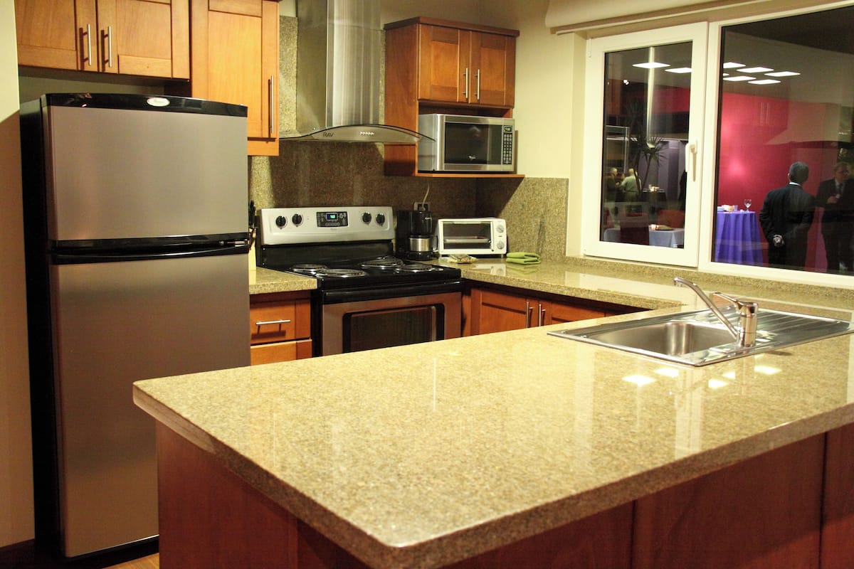 Una cocina con encimeras de granito, electrodomésticos de acero inoxidable y armarios de madera.