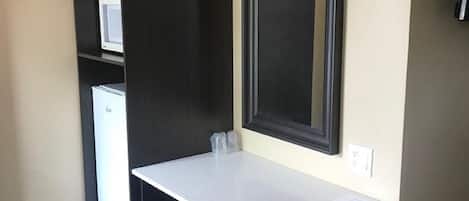 Una kitchenette compacta con encimera, un refrigerador y un microondas.