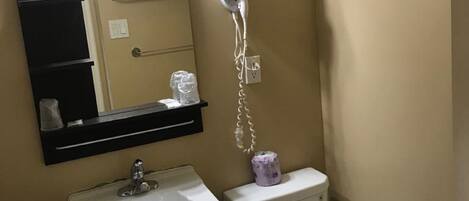 Een badkamer met een wit wastafel, toilet, haardroger en spiegel.