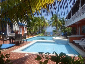 A pool area with lounge chairs, a small pool, and palm trees. - Hotel Sunset (San Andrés)