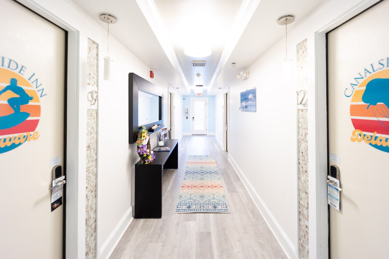 A hotel corridor with a reception desk, a TV, and a patterned rug.