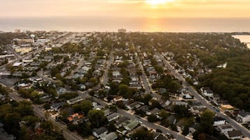 An aerial view of a residential area with houses, streets, and a water body in the background.