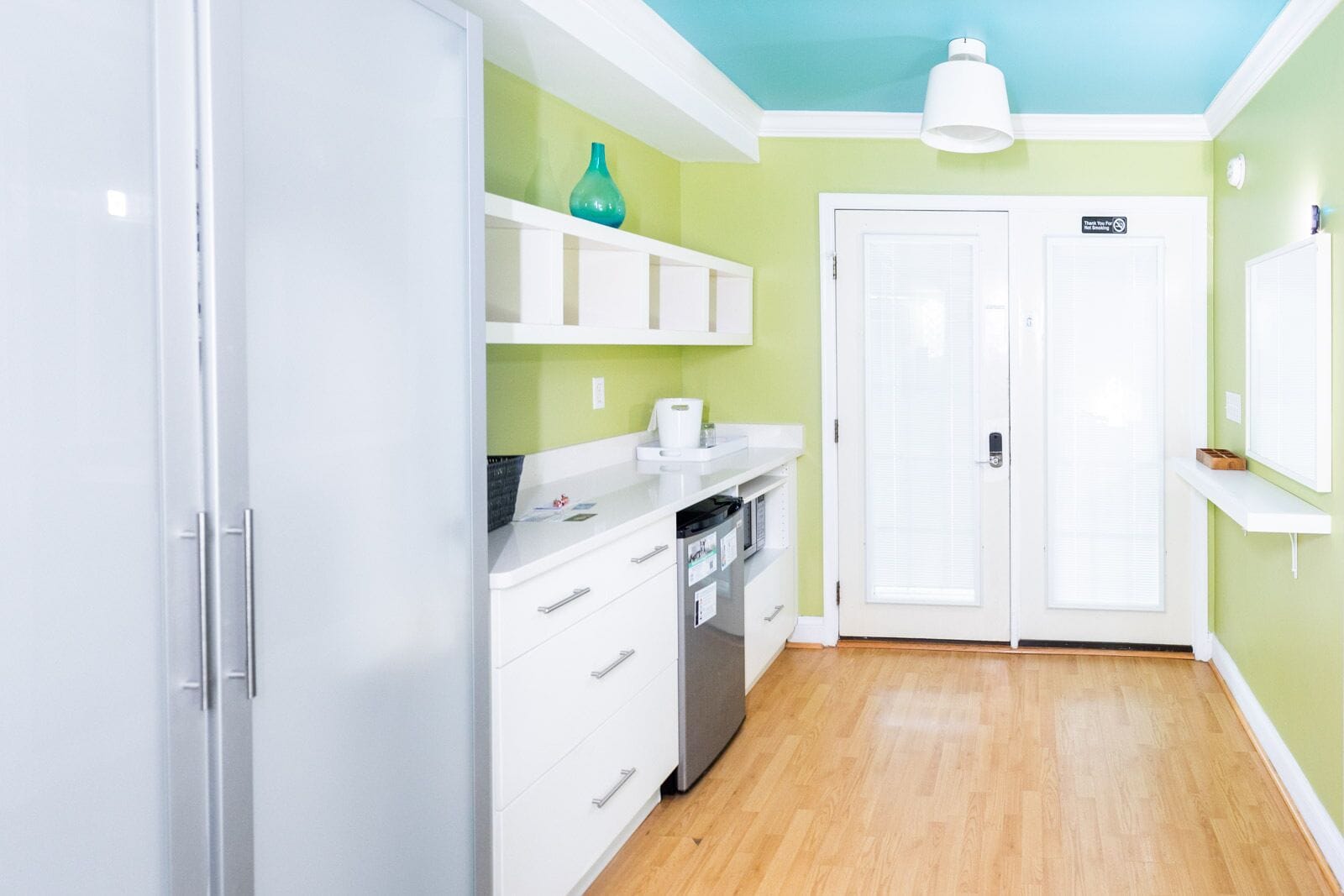 A kitchen with white cabinets, a teal vase, and a white ceiling light.