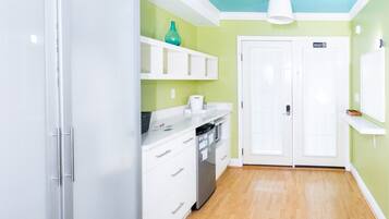 A kitchen with white cabinets, a teal vase, and a white ceiling light.
