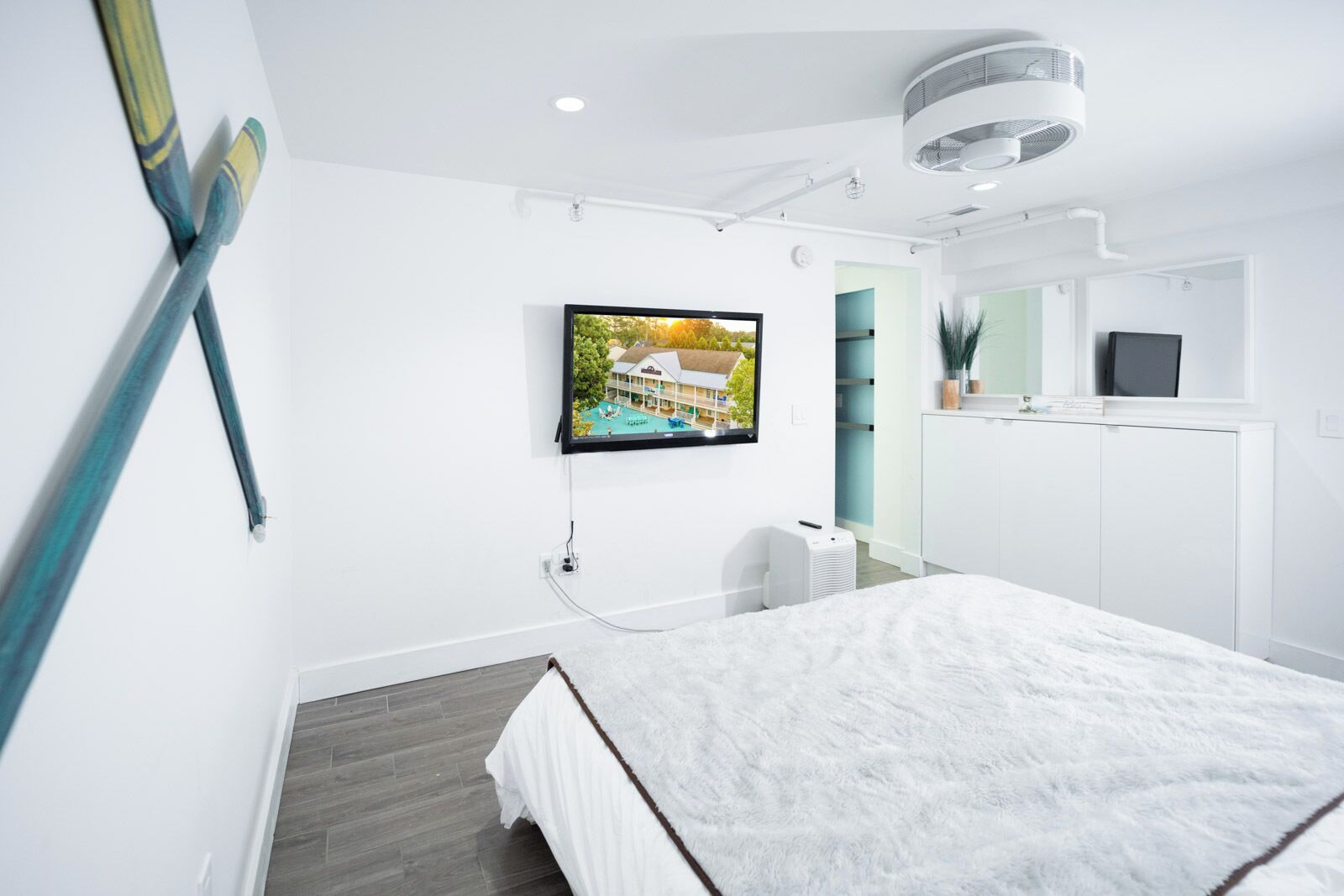 Una habitación de hotel moderna con una cama, un televisor de pantalla plana montado en la pared y un equipo de aire acondicionado instalado en el techo.