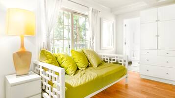 Une chambre avec un lit, une table de chevet, une commode et une fenêtre avec des rideaux.