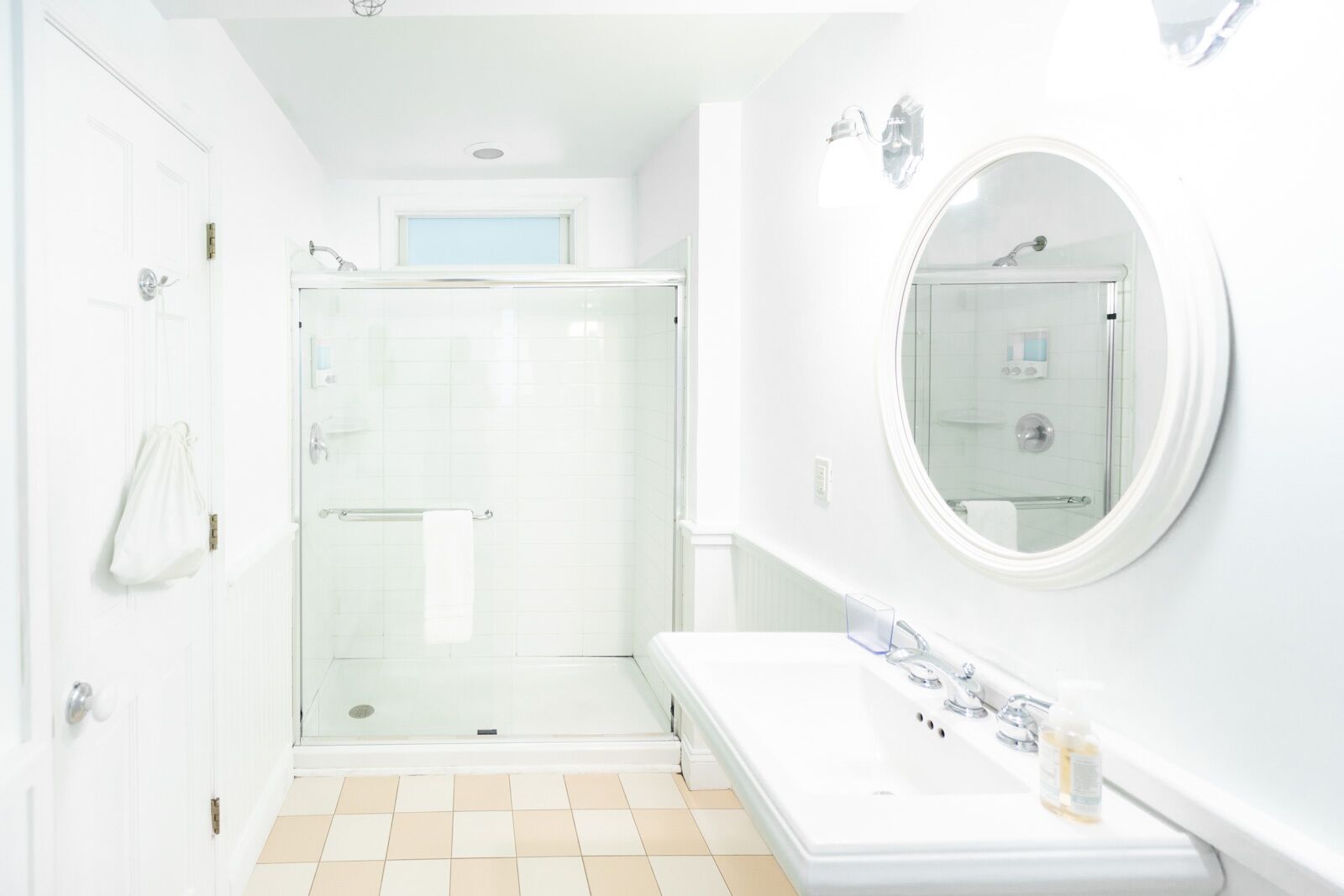 A modern bathroom with a glass-enclosed shower, a large mirror, and a white vanity with a sink.