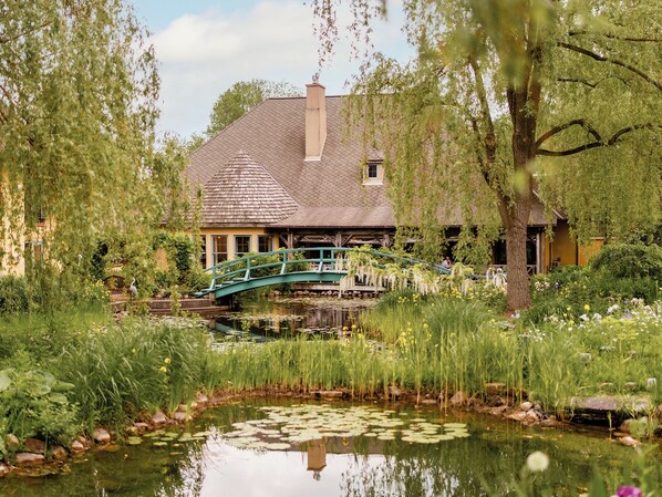 A house with a pond, a bridge, and lush greenery.