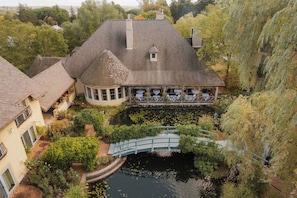 A large house with a pond, a bridge, and a small tower.