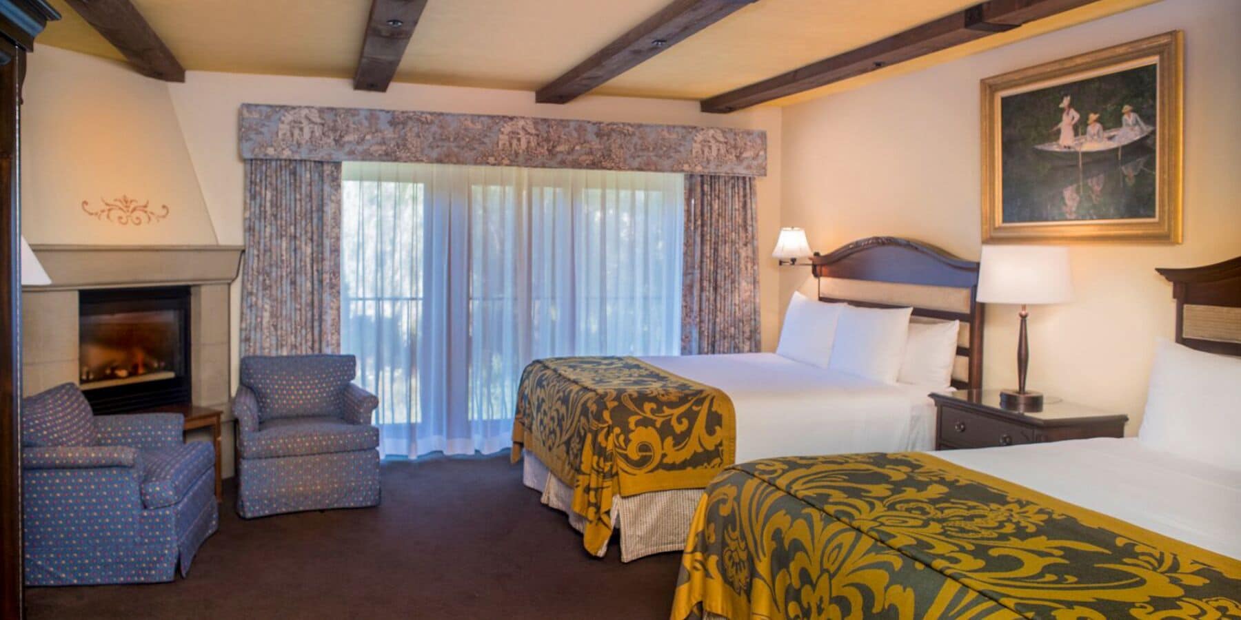 A hotel room with a fireplace, a bed, a sofa, and a painting on the wall.