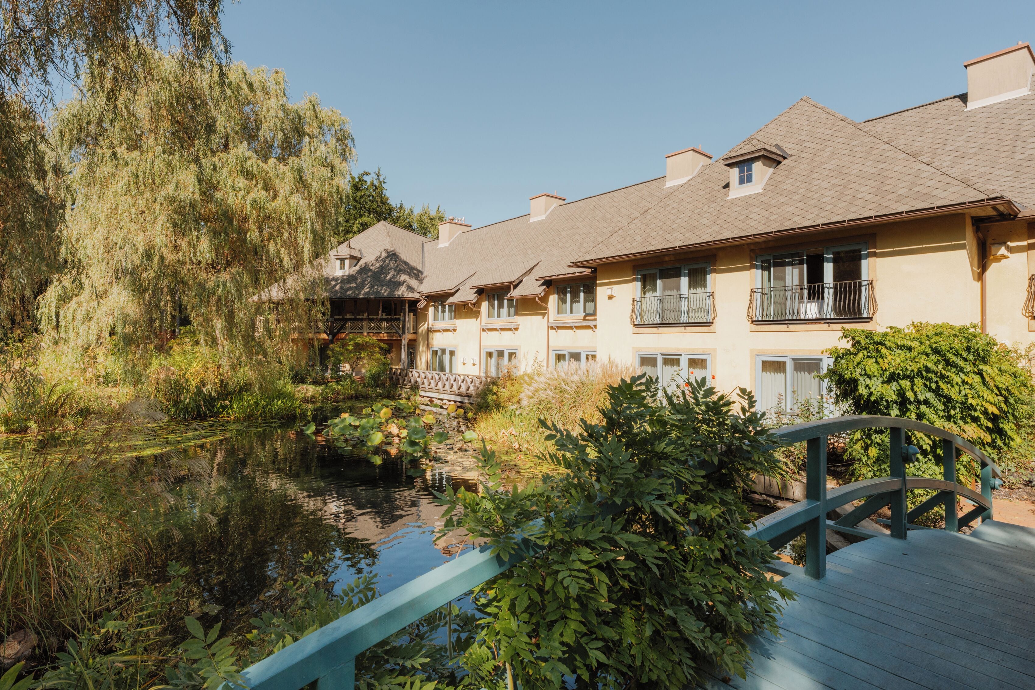 Un hôtel doté d’un étang, d’un pont en bois et d’une rangée de balcons.
