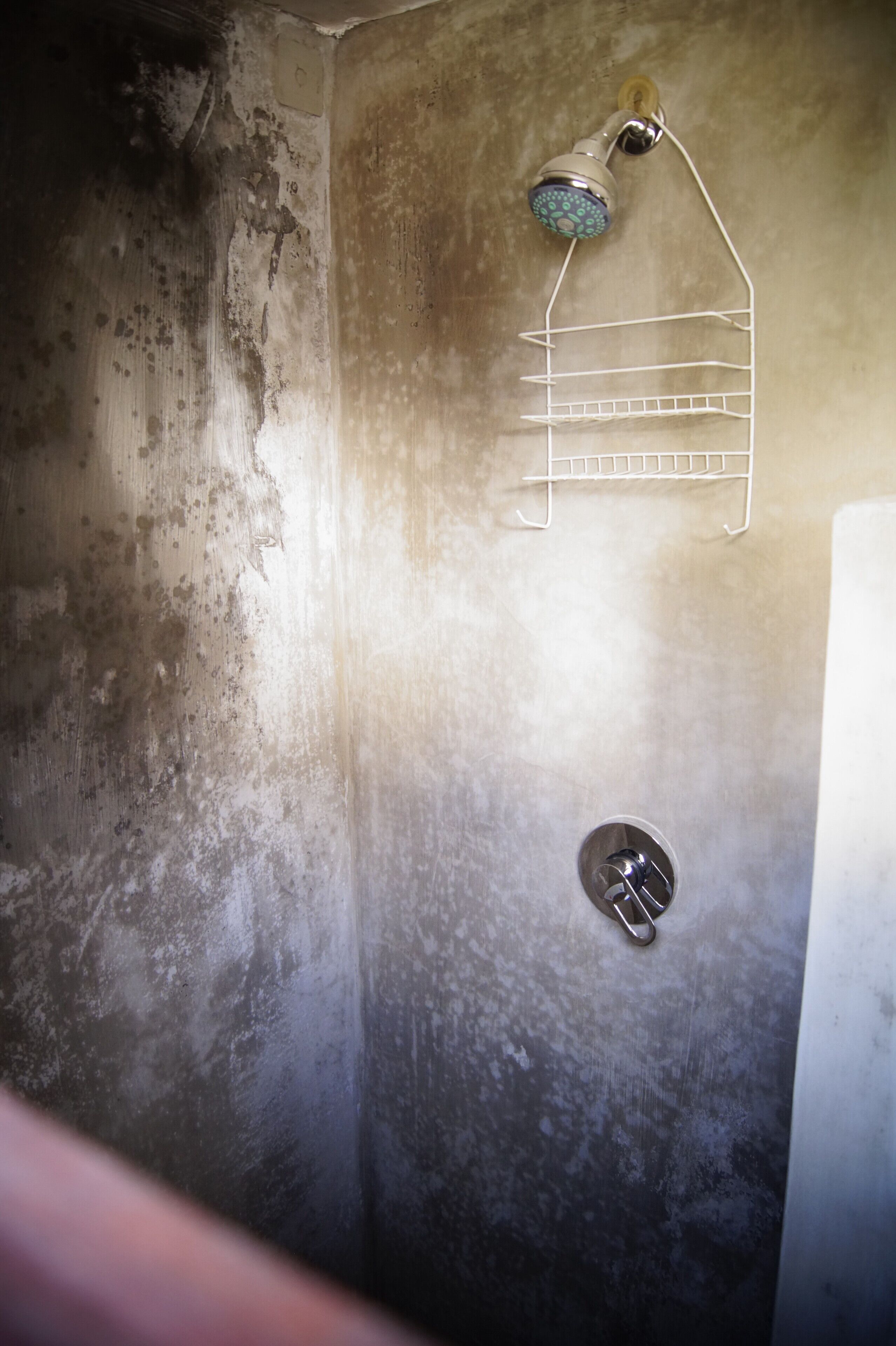 A bathroom with a shower, a metal rack, and a drain.