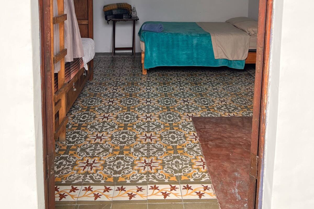 A room with a bunk bed, a small table with a bottle, and a hanging light fixture.
