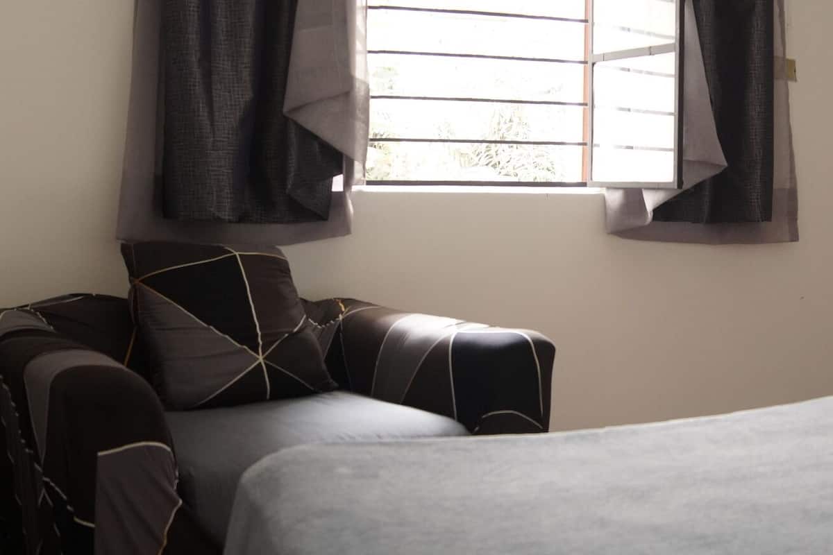 A room with two beds, a chair, and a window with curtains.