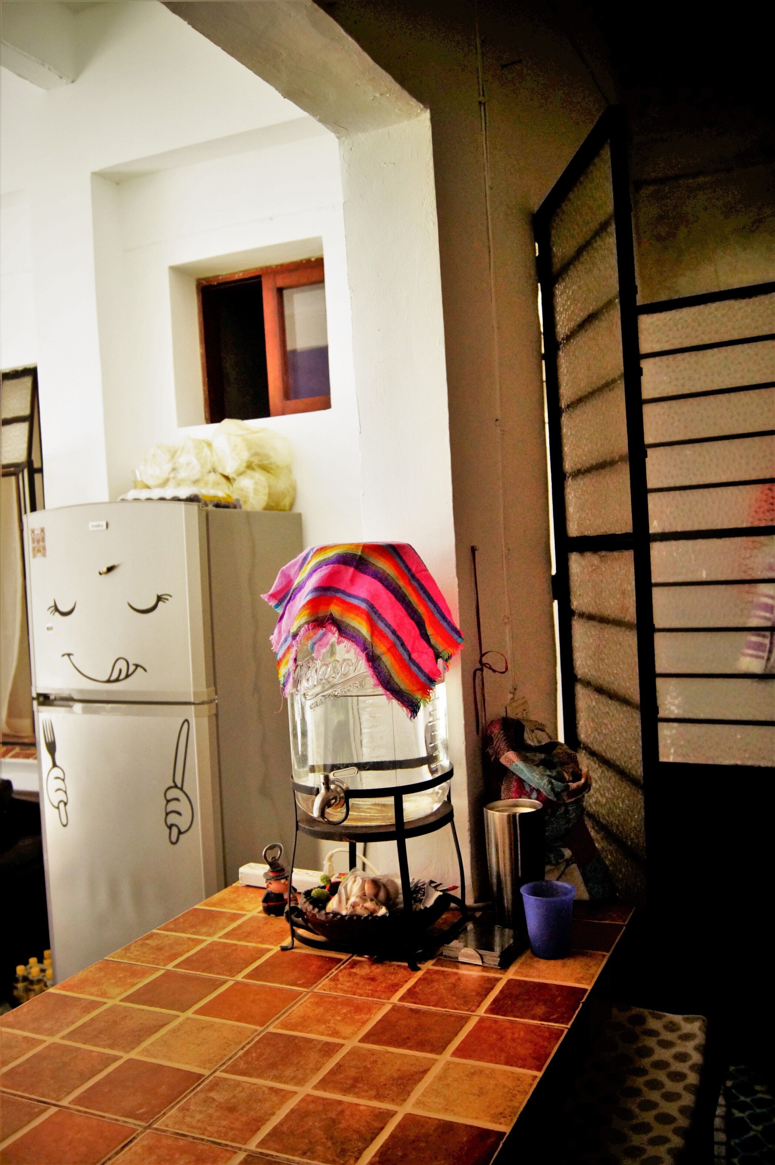 A kitchen with a refrigerator, a sink, and a window with blinds.