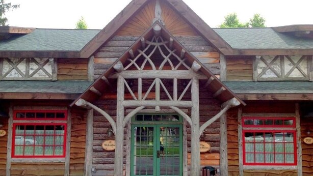 A log cabin with a green door and red-framed windows.