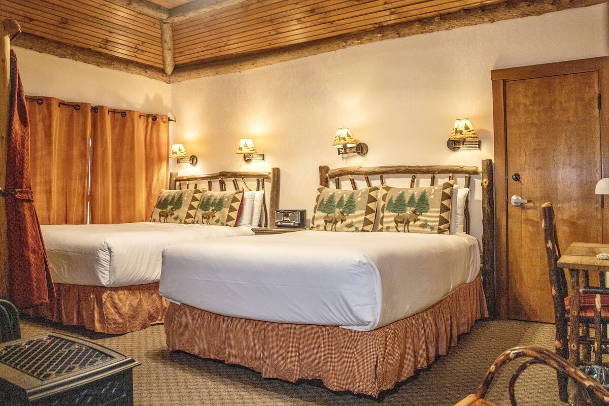 A room with two beds, wooden headboards, and wall-mounted lamps.
