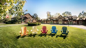 A lodge with a large lawn and colorful Adirondack chairs in front.