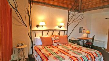 A cozy room with a bed, two wall-mounted lamps, a small table with a chair, and a telephone.