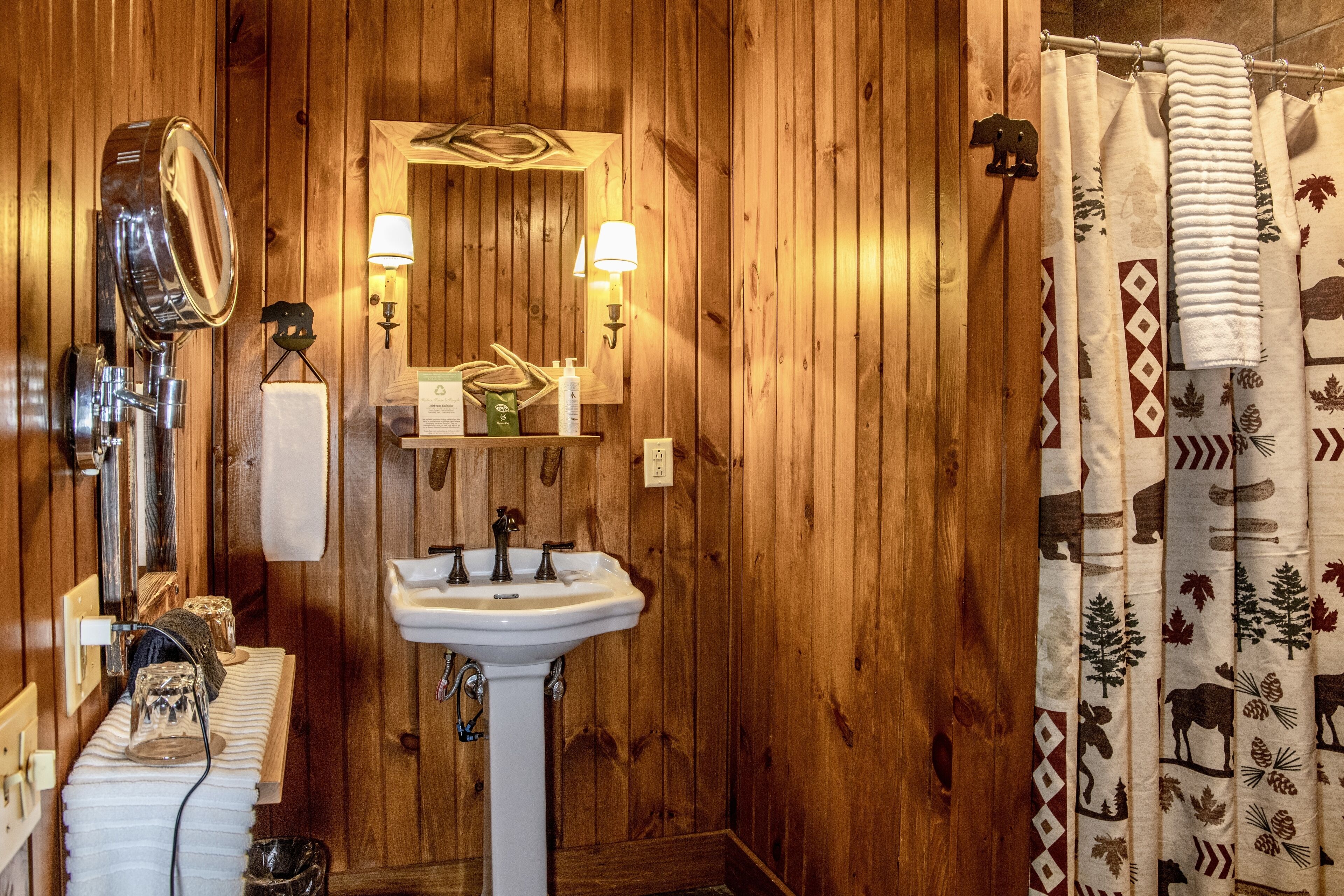 A wooden-paneled bathroom with a white sink, a mirror, and a shower curtain with animal prints.