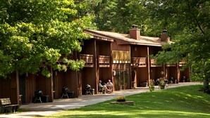 Eine Lodge mit überdachter Terrasse, Sitzgelegenheiten im Freien und einem gepflegten Rasen.