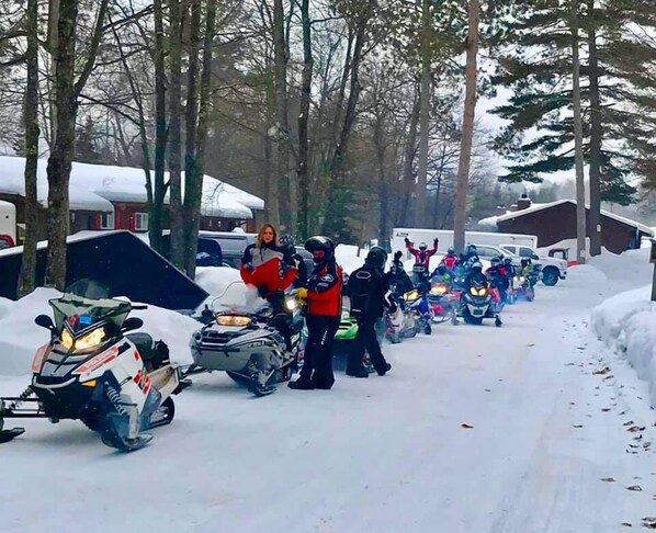 A snowmobile race with participants lined up on a snowy road. - Lake Forest Resort & Club (Eagle River)