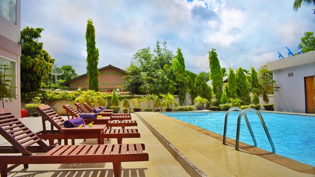 Zona junto a la piscina con sillones de madera y una alberca.