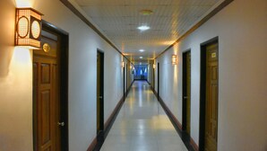 Un pasillo largo y bien iluminado con puertas a ambos lados, que conduce a habitaciones.