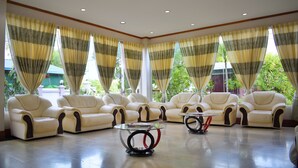 Una habitación amplia con ventanas grandes, varios sofás de cuero dispuestos en semicírculo y dos mesas de vidrio con base de metal.