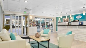 A reception area with a seating arrangement, a reception desk, and a view of the outside. - Brighton Suites Hotel (Rehoboth Beach)