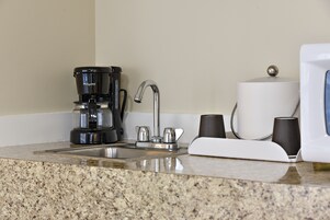 A kitchen with a coffee maker, a sink, and a roll of paper towels.