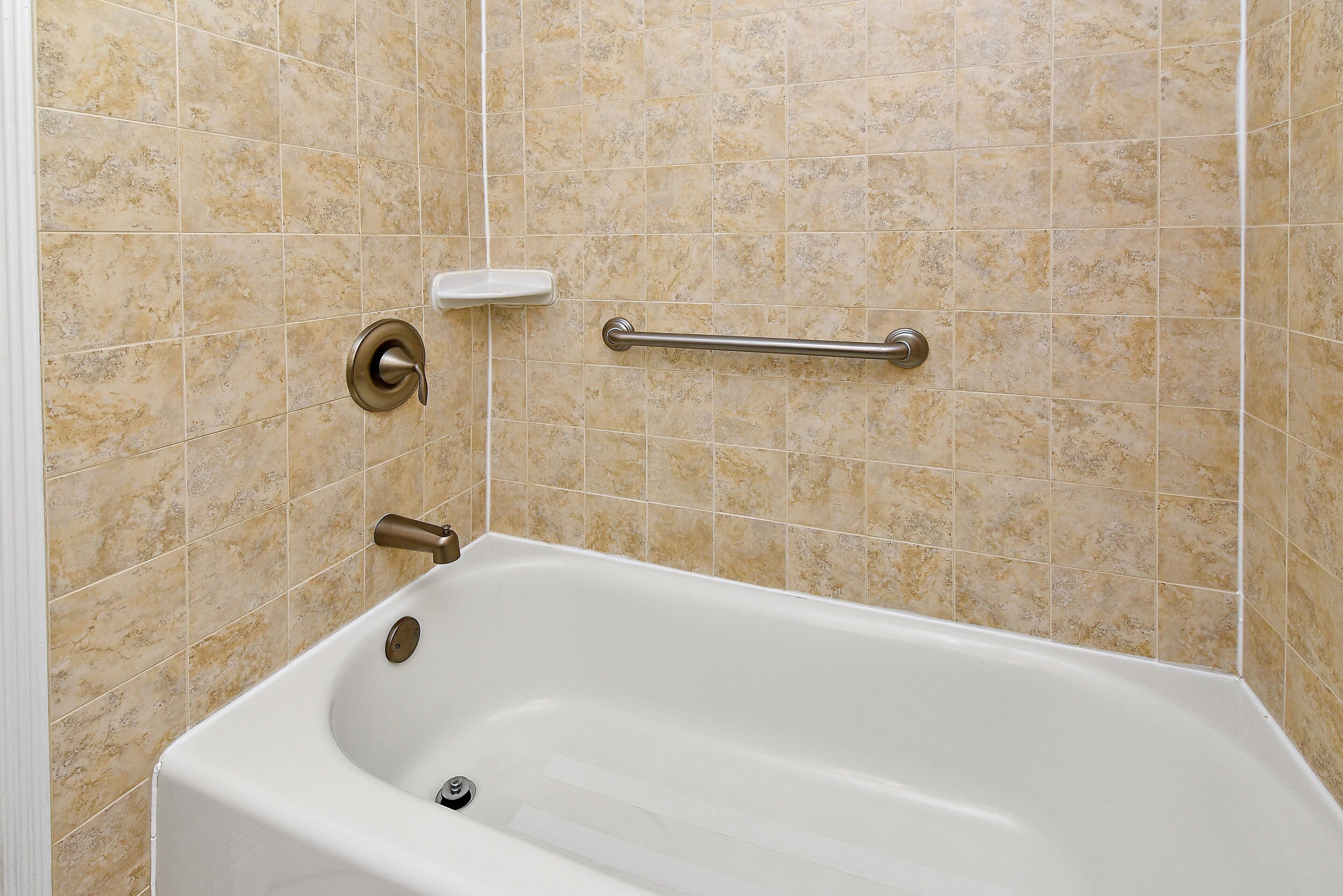 A bathroom with a bathtub, grab bars, and a towel rack.