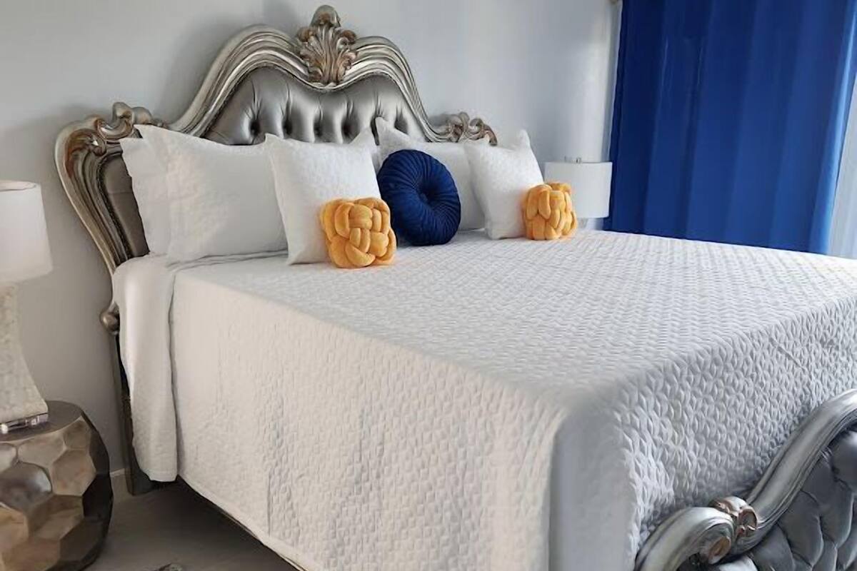 Une chambre à coucher avec un lit classique, une tête de lit décorative et un rideau bleu.