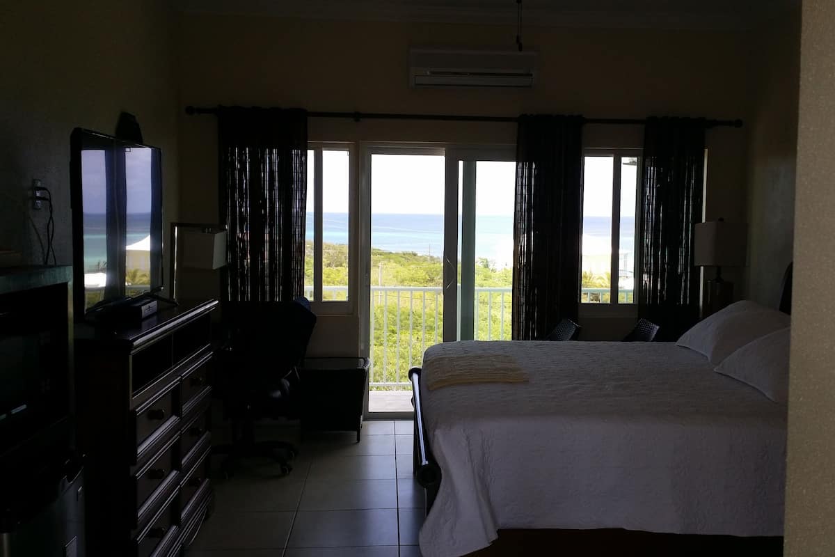 Une chambre d’hôtel avec un lit, un bureau, une chaise, une télévision et une vue sur l’océan.