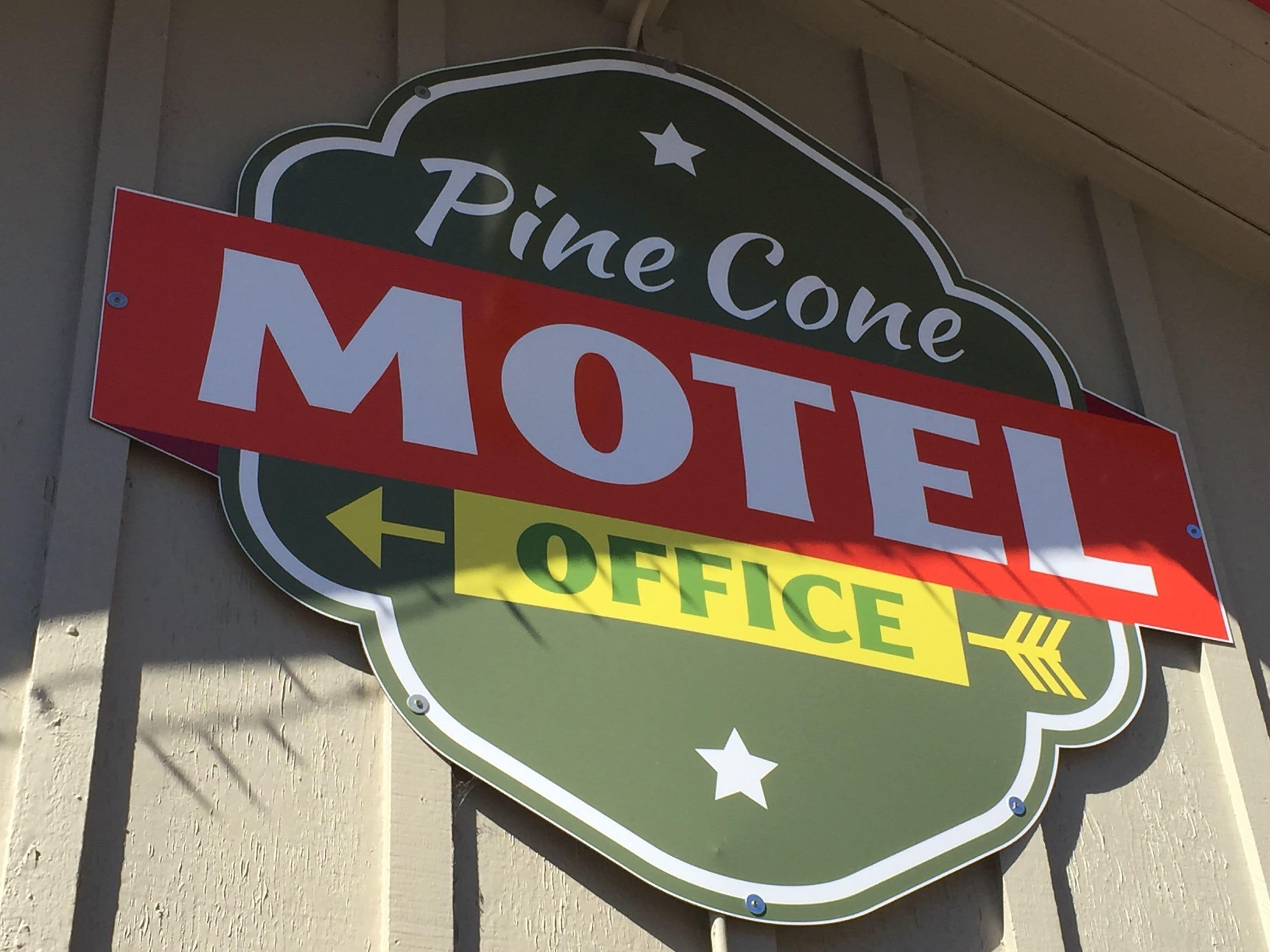 A Pine Cone Motel sign with a red banner and an arrow pointing left.