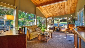 A spacious living area with a high ceiling, large windows, and a mix of seating arrangements including a sofa and chairs. - Piazza's Pine Cone Inn (Kernville)