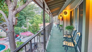 A covered balcony with outdoor seating, a tree, and a pool area. - Piazza's Pine Cone Inn (Kernville)