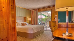 A hotel room with a bed, a desk, a chair, and a view of the outside. - Piazza's Pine Cone Inn (Kernville)