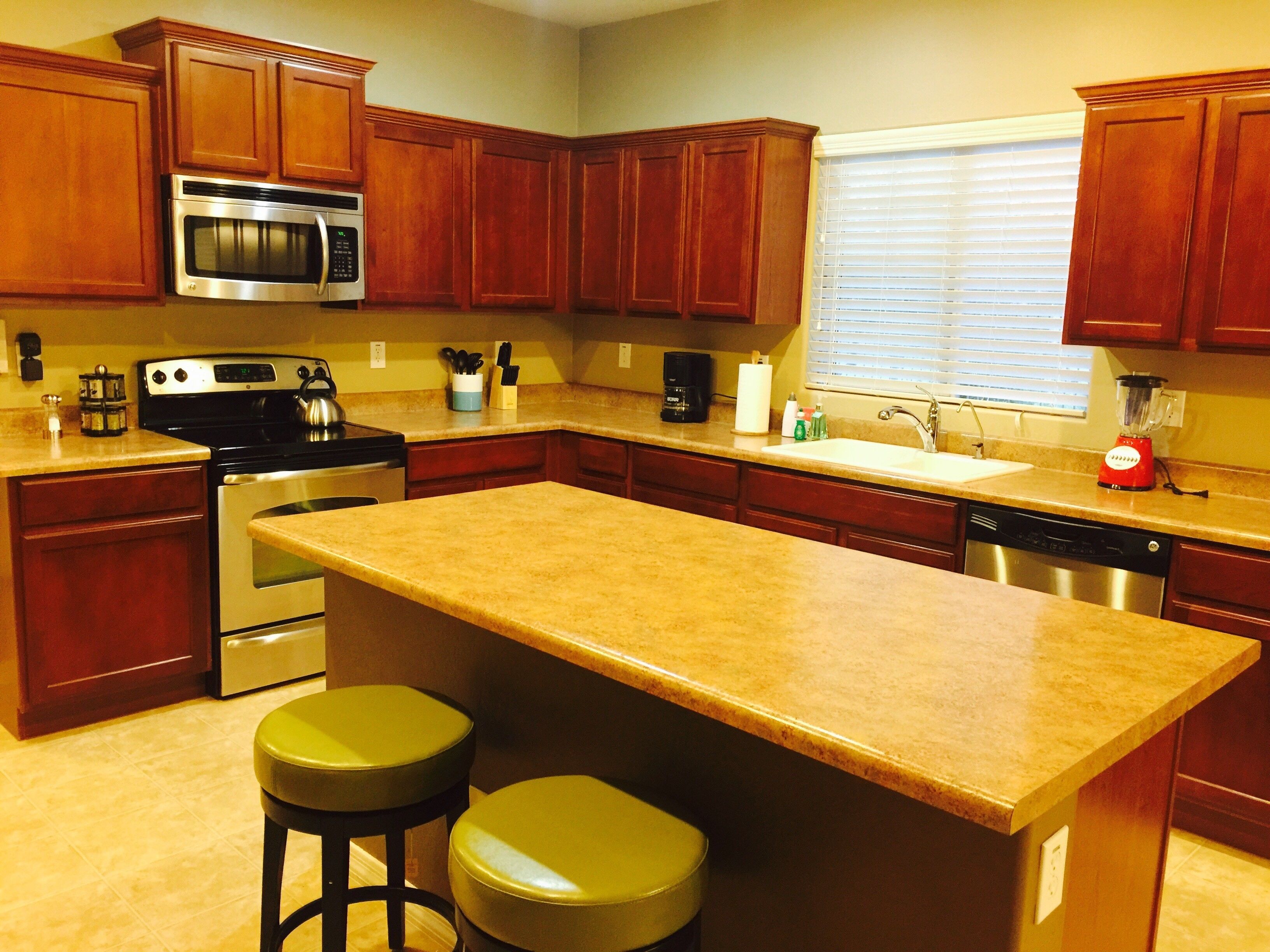 A kitchen with wooden cabinets, a stainless steel oven, a microwave, a coffee maker, and a blender.