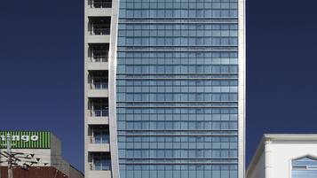 Een modern Benikea Hotel met een opvallende, gebogen glazen gevel en meerdere balkons.